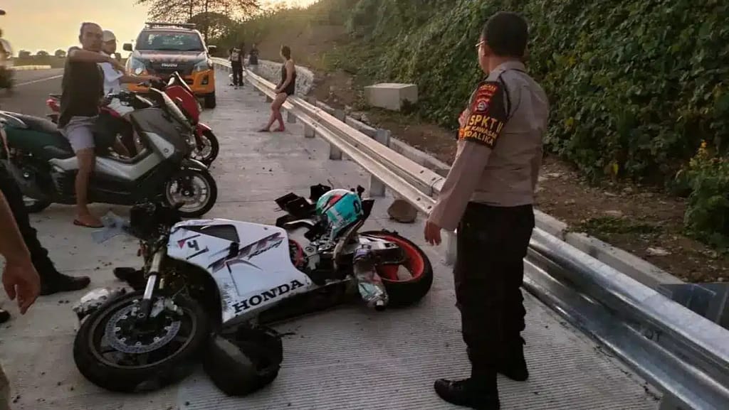 Destroyed sports bike after crash into Bali road barrier with police officer present - severe scooter accident aftermath