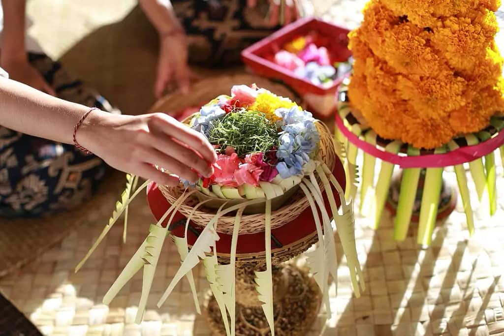 photo of a woman arranging flower arrangements in a canang sari to match the required position according to color and cardinal direction