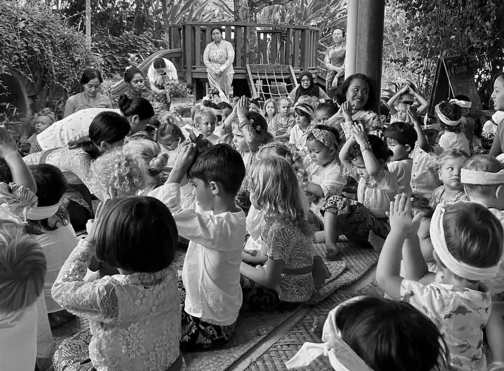 A group of 3 to 5 year old Caucasian children complete with Balinese traditional clothes are seen worshiping after praying and offering canang sari. looks cute and profound