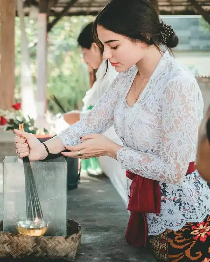 Photo of Balinese woman burning incense as an offering