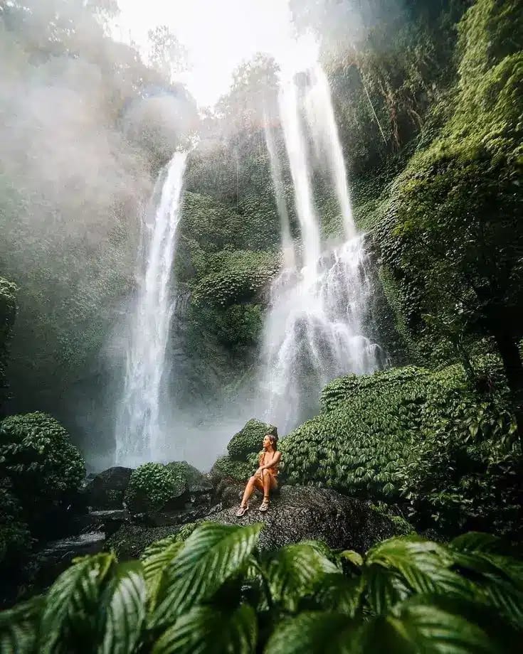 A female tourist poses at a waterfall in northern Bali.