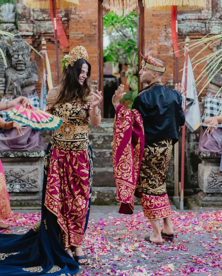 a Caucasian couple in traditional Balinese clothes are dancing with Balinese dancers 