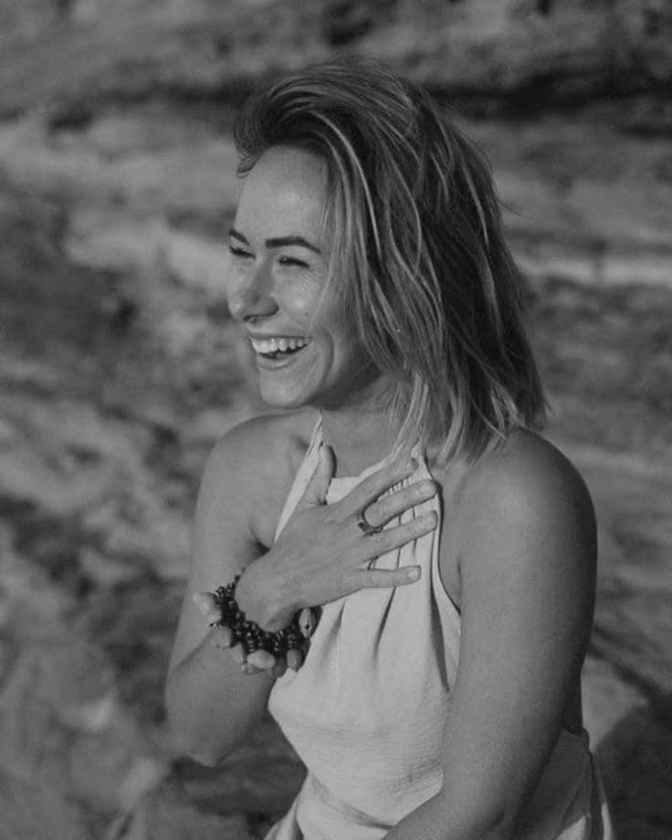 black and white photo of a woman putting her right hand on her chest while smiling broadly as a symbol of suksma mewali or You are welcome