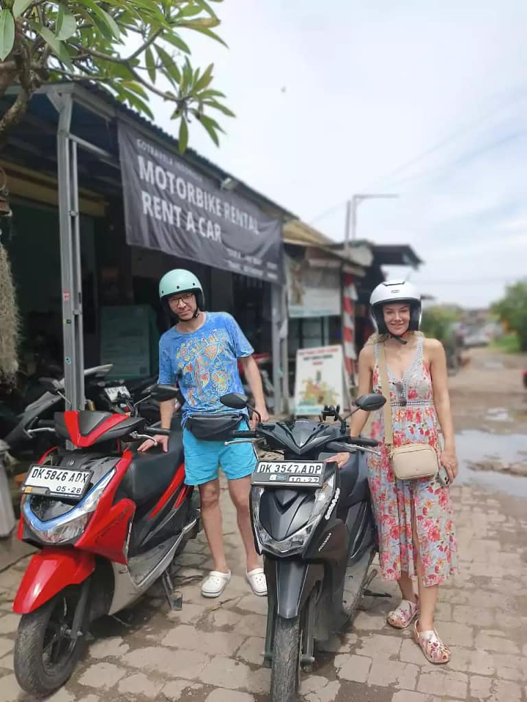 Two tourists smiling with rented scooters at Hey Bali Rental shop in Kuta - affordable motorbike hire in Bali with helmets included - Honda Vario 125cc for rent in Kuta - Ideal for long Bali road trips