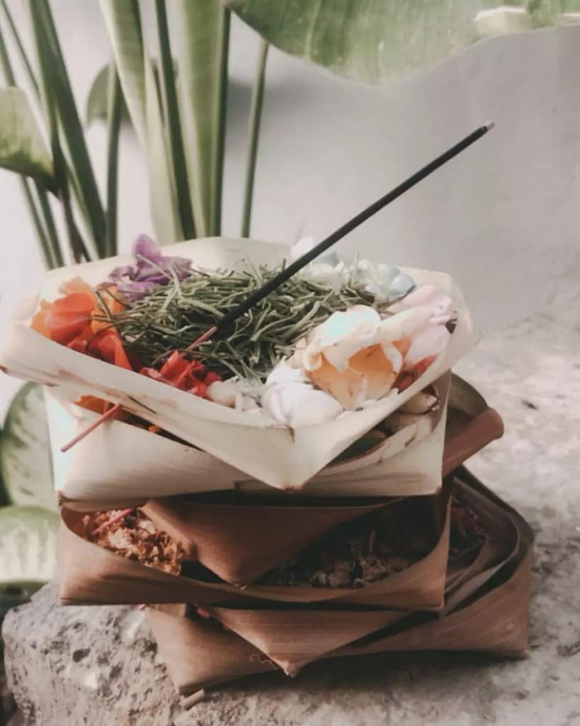 Photo of 6 stacked canang sari and incense on top as thanksgiving and gratitude to the divine.  - bali hindu offerings