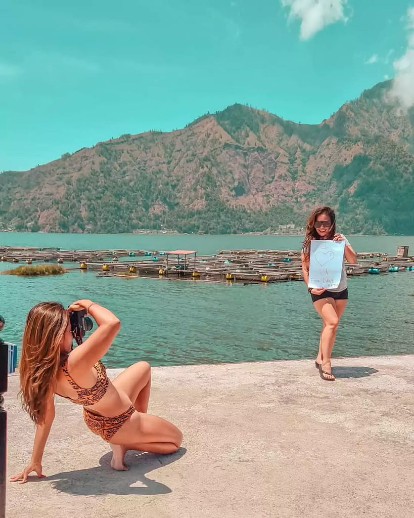 two female tourists take a photo on the edge of Lake Batur in Bali.