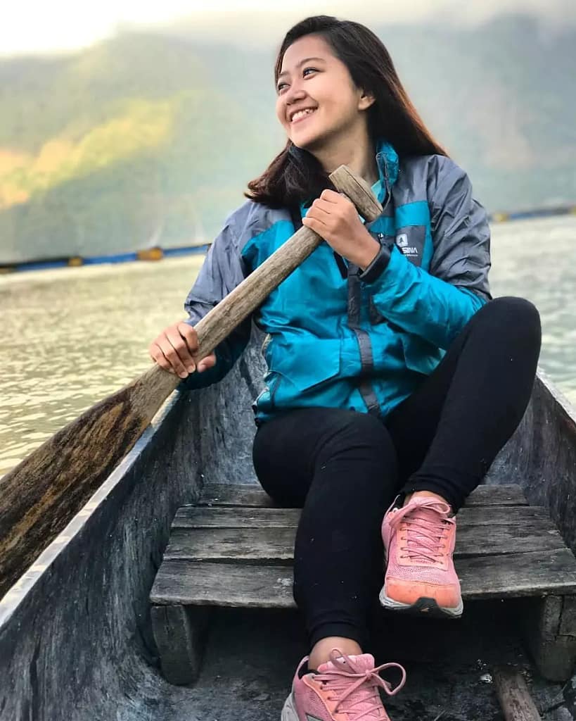 
an Indonesian tourist paddling a traditional boat in the morning in the middle of the beautiful batur lake.