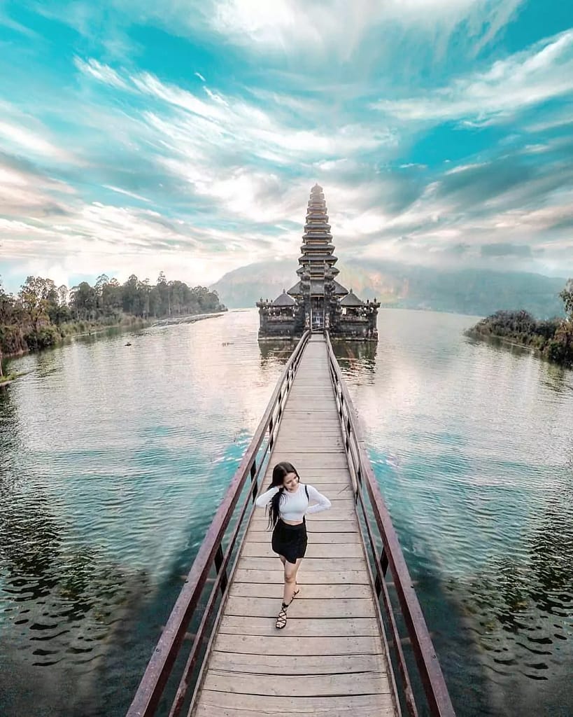 beautiful photo of a woman posing on the bridge of batur temple with a view of batur lake in bali