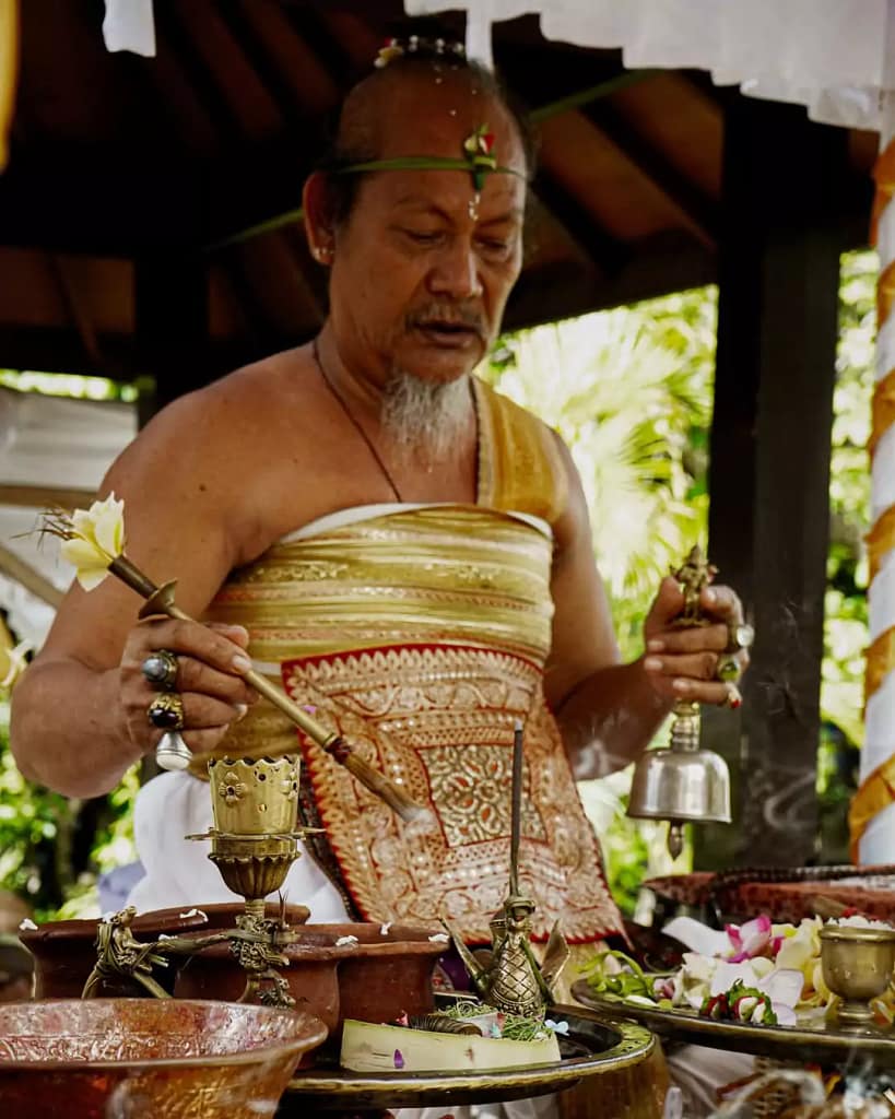 what religion in bali - a priest in bali praying and reading mantras with peaceful humming
