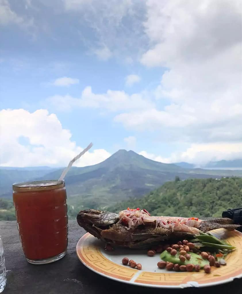 photo of grilled fish with sambal matah and sweet tea with the background of the lake and Mount Batur which is one of the favorite menus there.