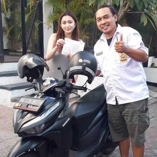Staff and tourist holding rental contract for motorbike in Bali - successful negotiation for cheap scooter hire - Trusted Bali scooter rental shop in Ubud - Verified by HeyBali 2025