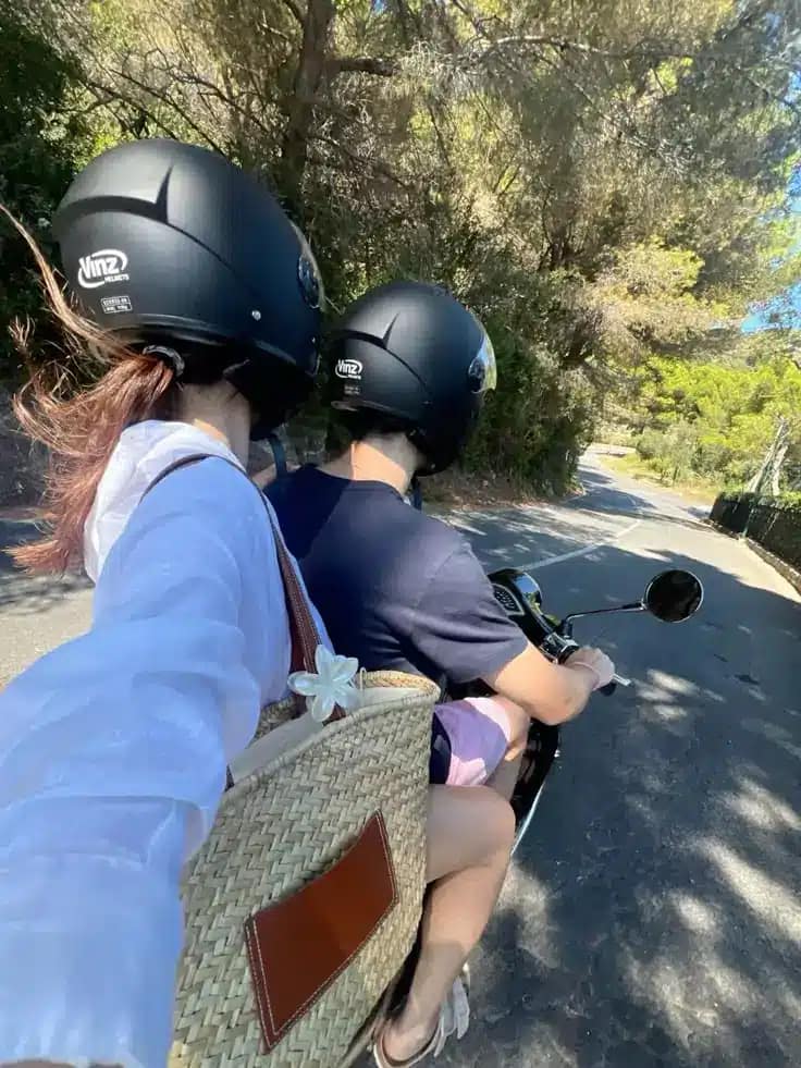 ourist couple wearing helmets correctly while riding scooter in Bali - demonstration of safe motorbike rental practices"