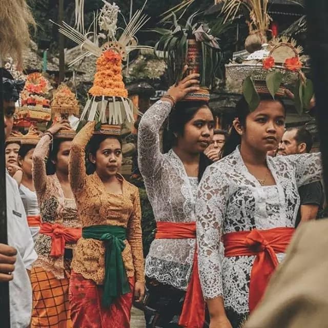 photo of several Balinese women in full traditional dress walking to the temple carrying pejati, banten and canang sari on their heads.