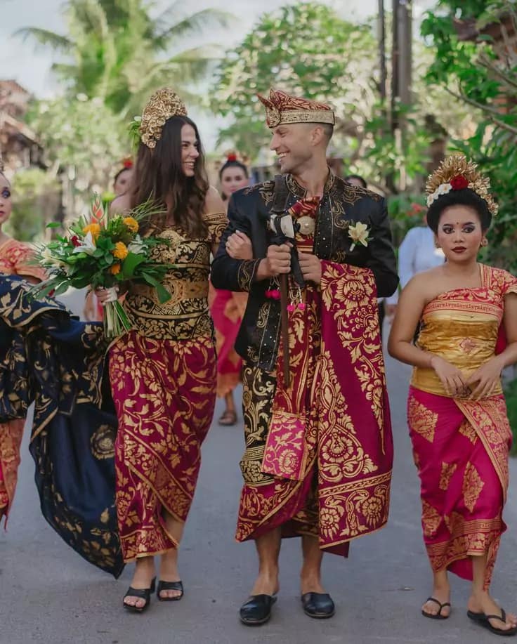 photo of the bule bride and groom who got married using Balinese customs and dressed in luxurious Balinese traditional clothes walking to the location of the wedding ceremony accompanied by Balinese girls