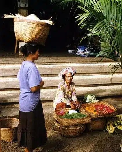 A Balinese grandmother is selling canang sari at the market