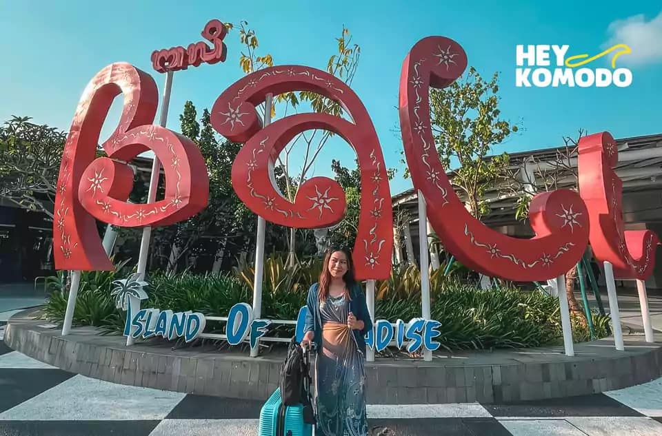 photo of a female guest taking a photo at a sign that says welcome to Bali