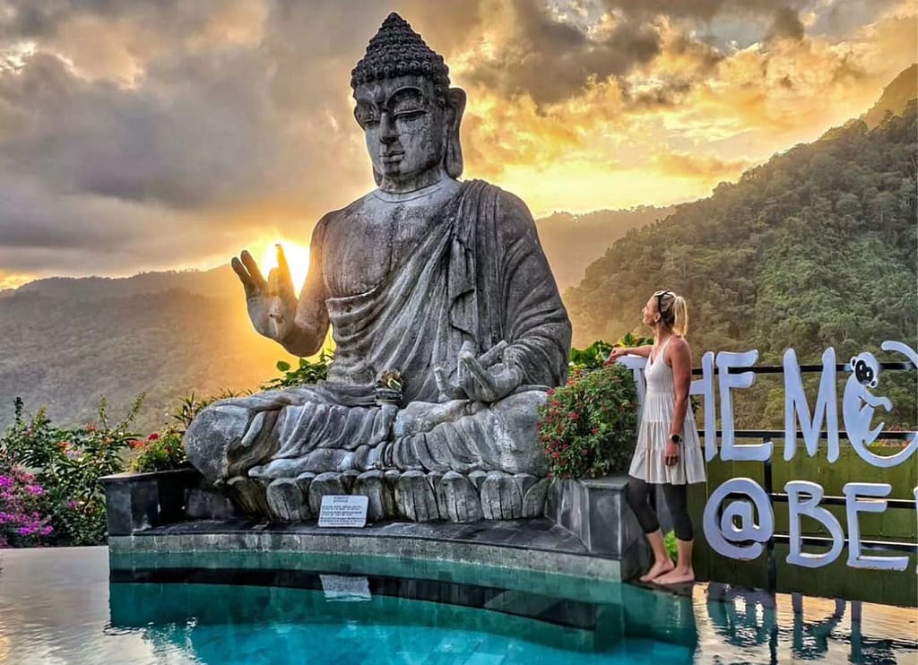 A female tourist from Russia looks at a Buddha statue beside the swimming pool at a restaurant in Kelungkung, Bali. - first time in Bali